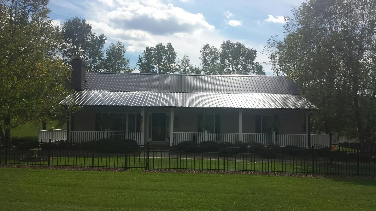 Gray metal roof on a brick ranch with a full width front porch — Gutter Guard Installation work by our crew in Palisade