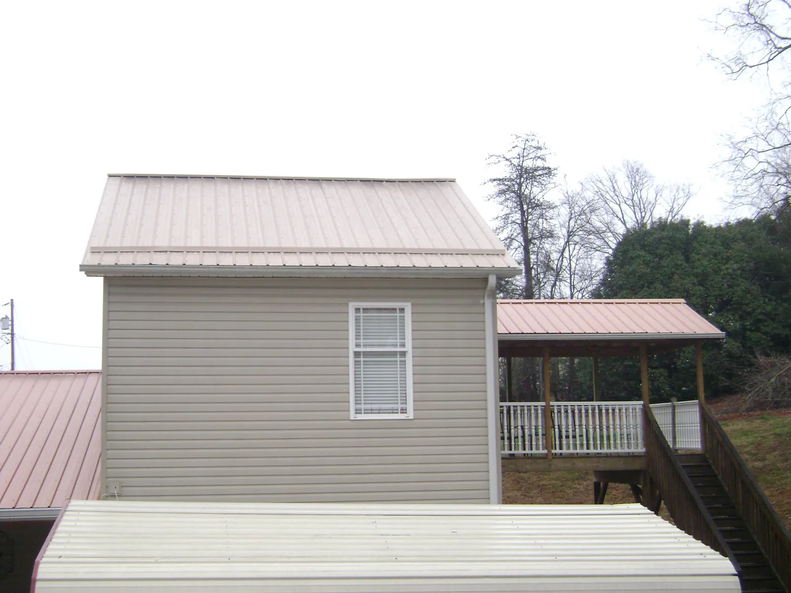 Tan metal roofs on a two story addition and attached porch, from a Roof Replacement job in Palisade