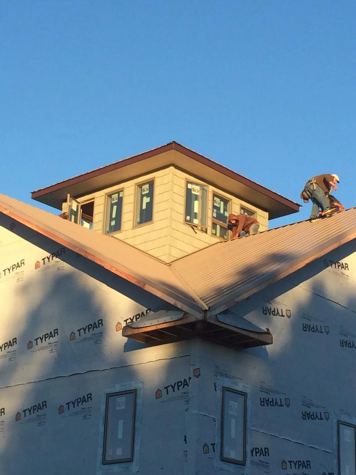 Roofers working around a rooftop cupola on a new metal roof at sunset — Roof Waterproofing in Palisade by Roofing Brothers